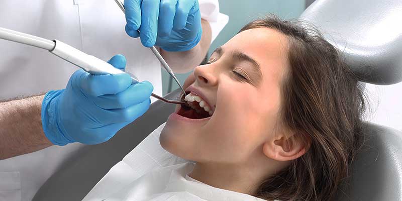 children's dentist cleaning little girl's teeth