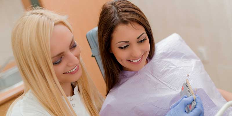 woman choosing dental veneer colours in dentist office