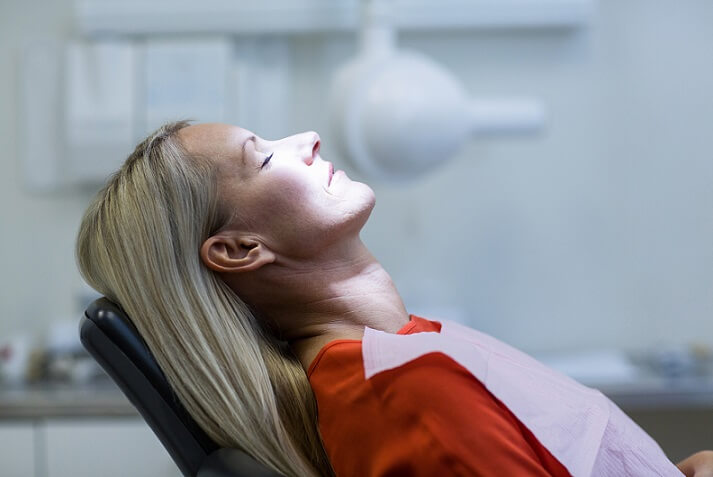 man in dental office after tooth replacement treatment with a dental crown