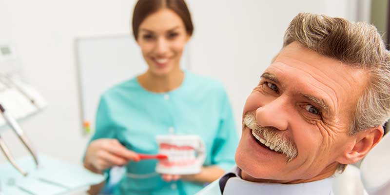 man in dental office after tooth replacement treatment with a dental crown